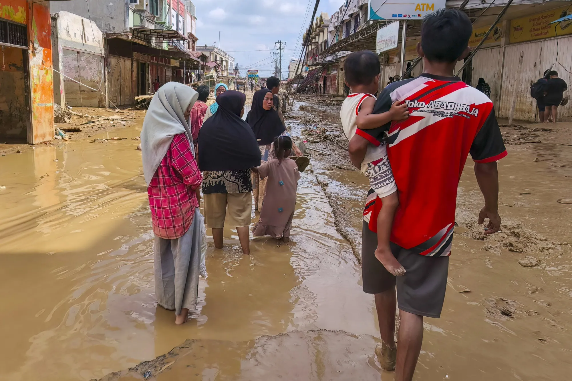 Flood-affected residents walk along a muddy road in North Sumatra, Indonesia on Dec. 2.