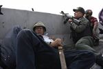 A protester takes cover behind a concrete barrier beside a National Guard member supporting Venezuelan opposition leader Juan Guaido during a military uprising near the La Carlota base.