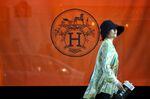 A pedestrian is reflected in a Hermes store window, the company is operated by Hermes International SCA.