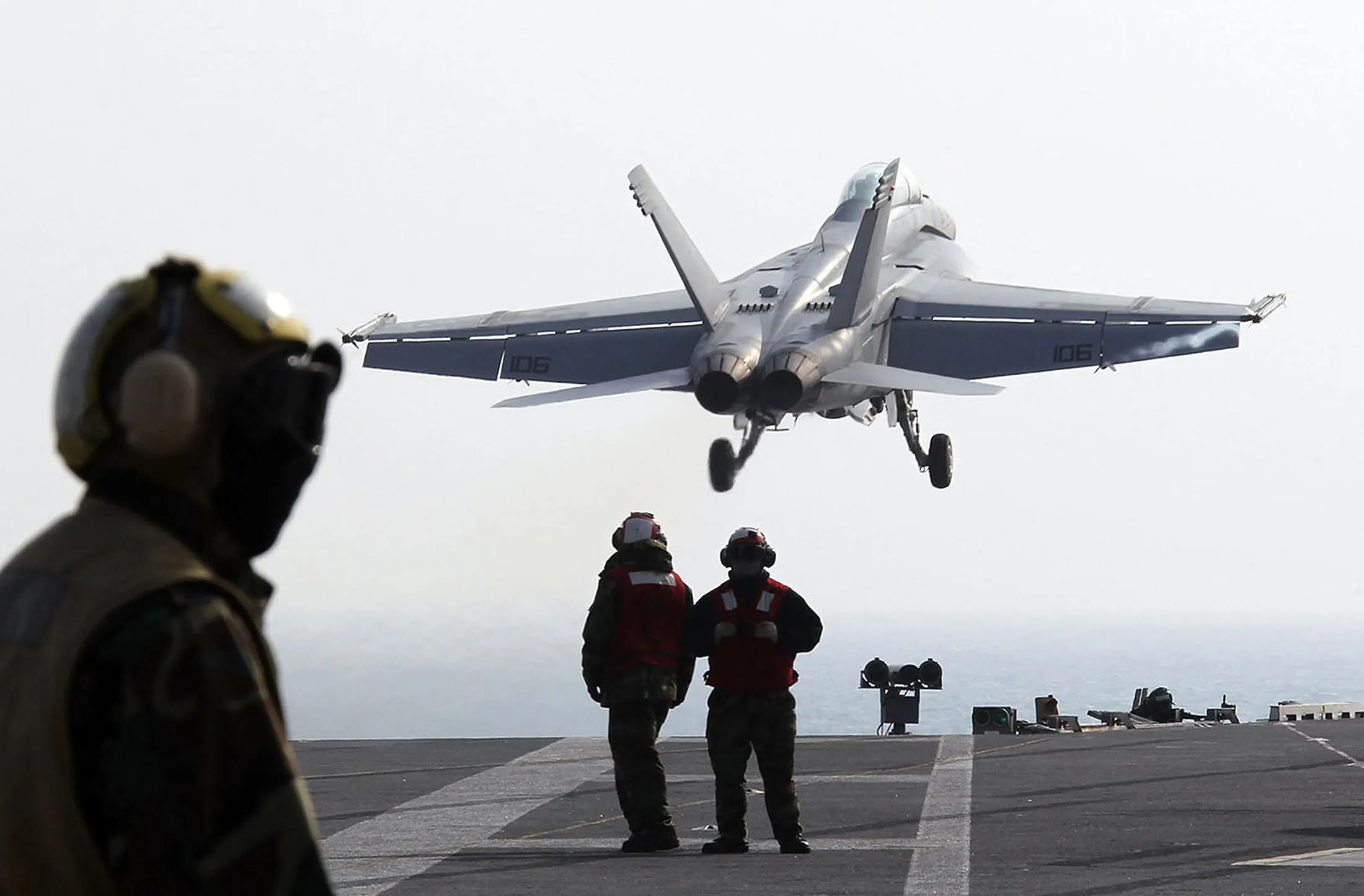 US Navy crew members stand on deck as a F-18 Super Hornet strike fighter plane takes off from the deck of USS George Washington during a joint US and South Korea military exercise on the Korean Peninsula's west sea on November 29, 2010 South Korea.
