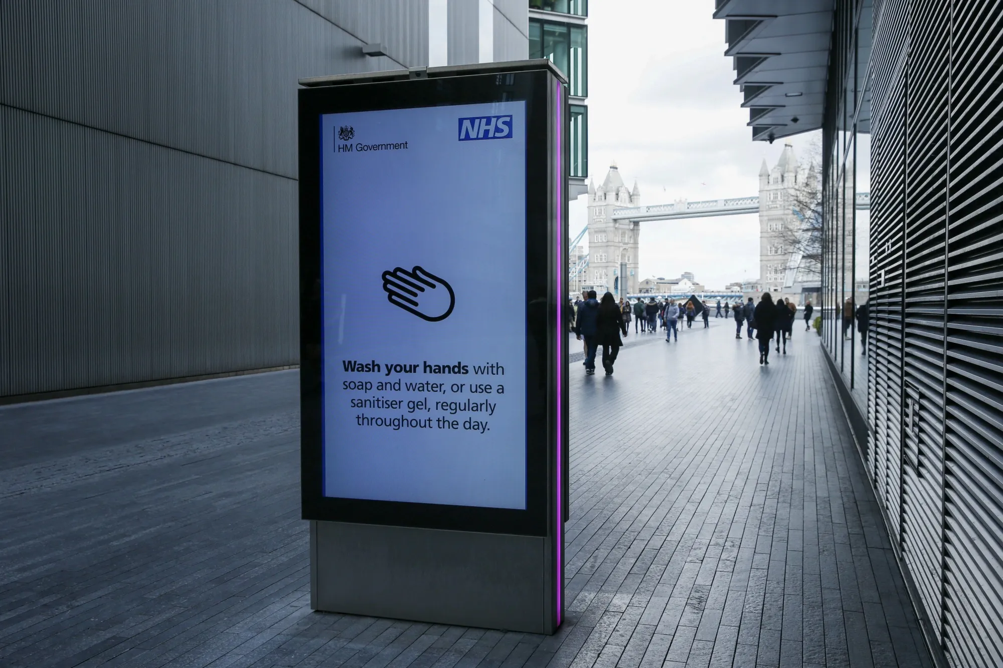 Pedestrians walk past a sign displaying a U.K. government coronavirus information notice in London on March 13.