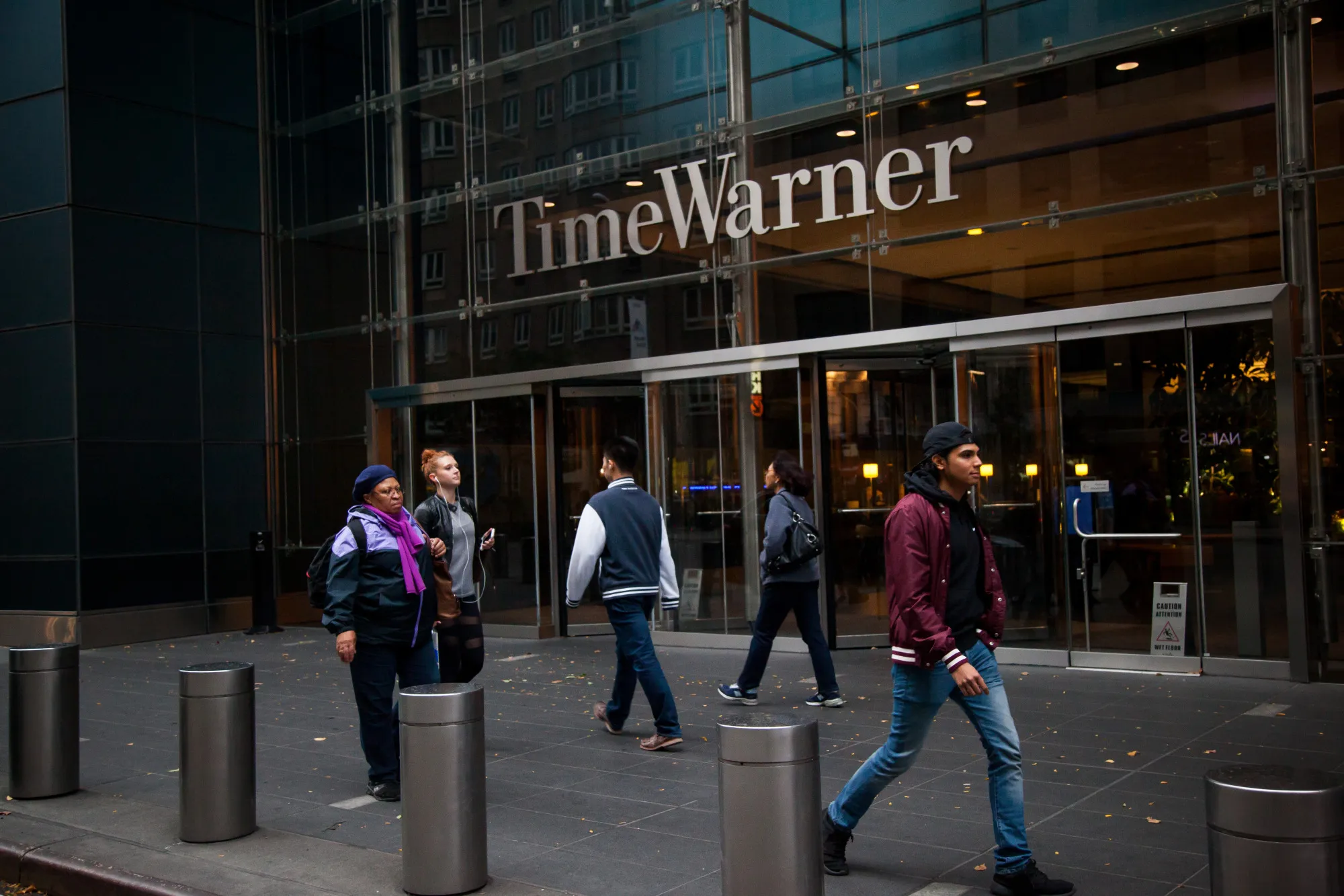 Pedestrians walk past the Time Warner Inc. Center in New York, U.S., on Saturday, Oct. 22, 2016. According to a statement Saturday, AT&T agreed to buy Time Warner for $107.50 a share.