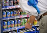 A customer picks up a can of Kirin Brewery Co.'s Strong Hyoketsu drink at a Lawson Inc. convenience store in Tokyo.