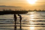 Children play in the sea in front of the mangroves of Ha Pak Nai with the city of Shenzhen in background.