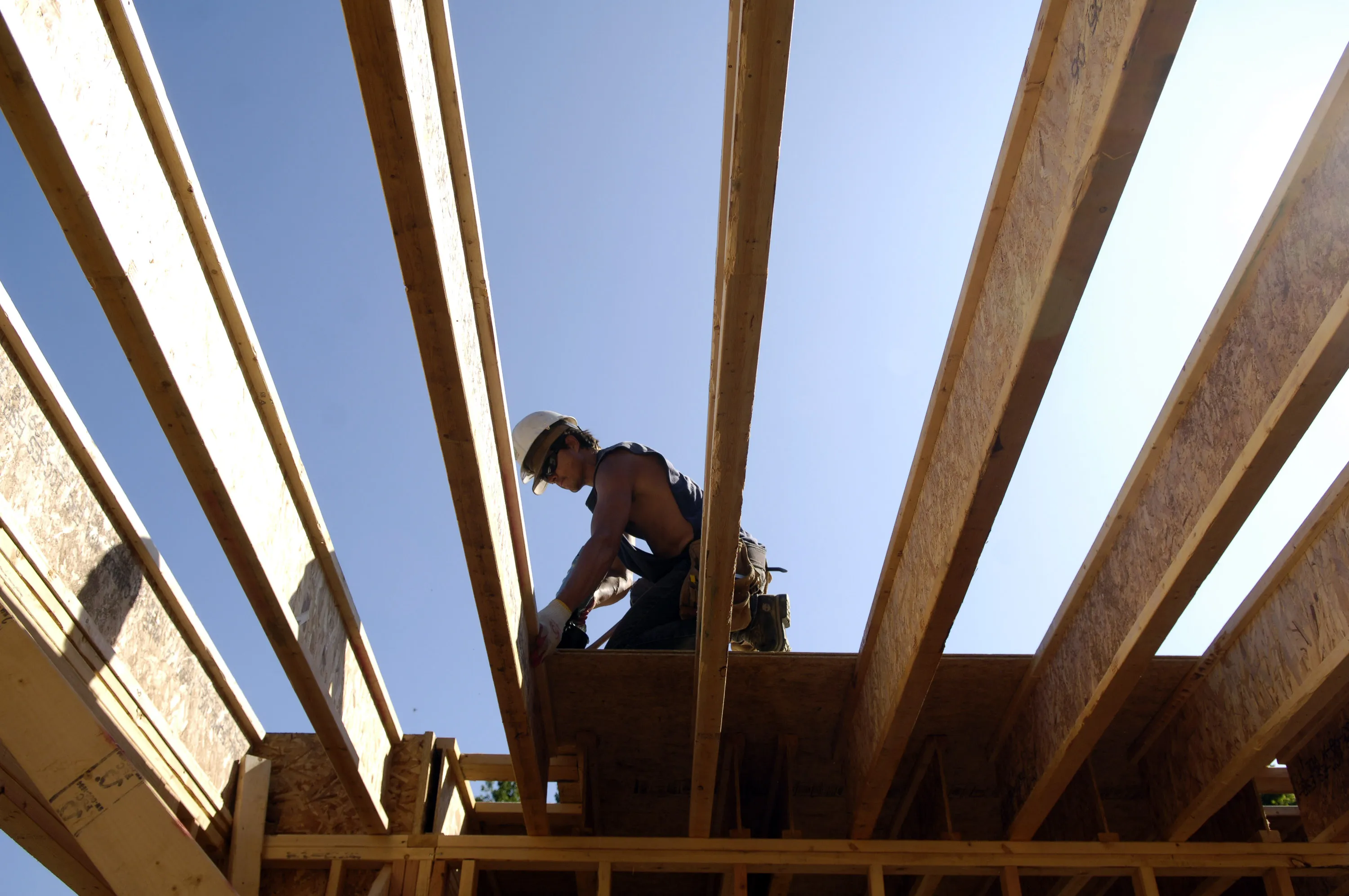 A worker nails down a plywood on a new home.