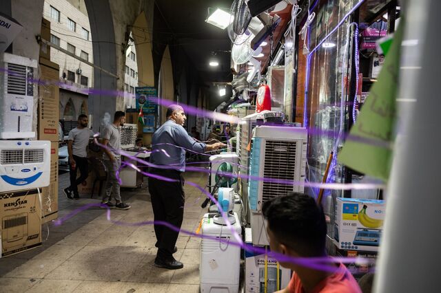 A shop owner cools himself in front of a display AC units and fans outside his store in Amman, Jordan.