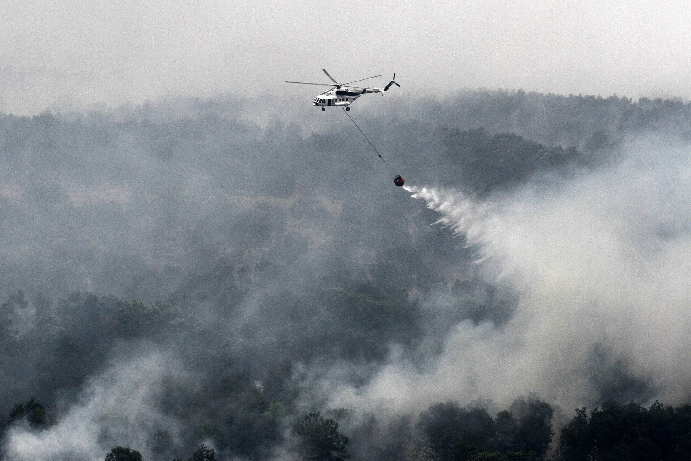 An Indonesian helicopter water-bombs a fire spot in South Sumatra province.

