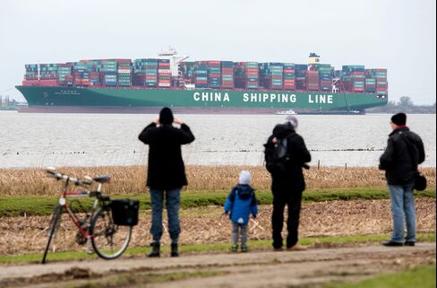Strollers look at the containership stranded in the River Elbe