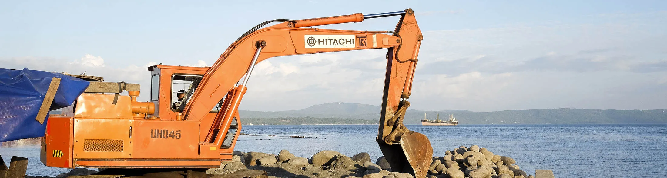 A Hitachi Construction Machinery Co. excavator moves stones at a coastal wall in the Isla Verde shantytown of Davao, Mindanao, the Philippines, on Friday, Dec. 11, 2015. Davao city's reputation as one of the safest, most vibrant and best-run cities in the country is drawing migrants and business people in their thousands. It has become a victim of its own success, and an archetype of modern urbanization in developing countries, where inward migration is outstripping governments' ability to supply infrastructure and services.
