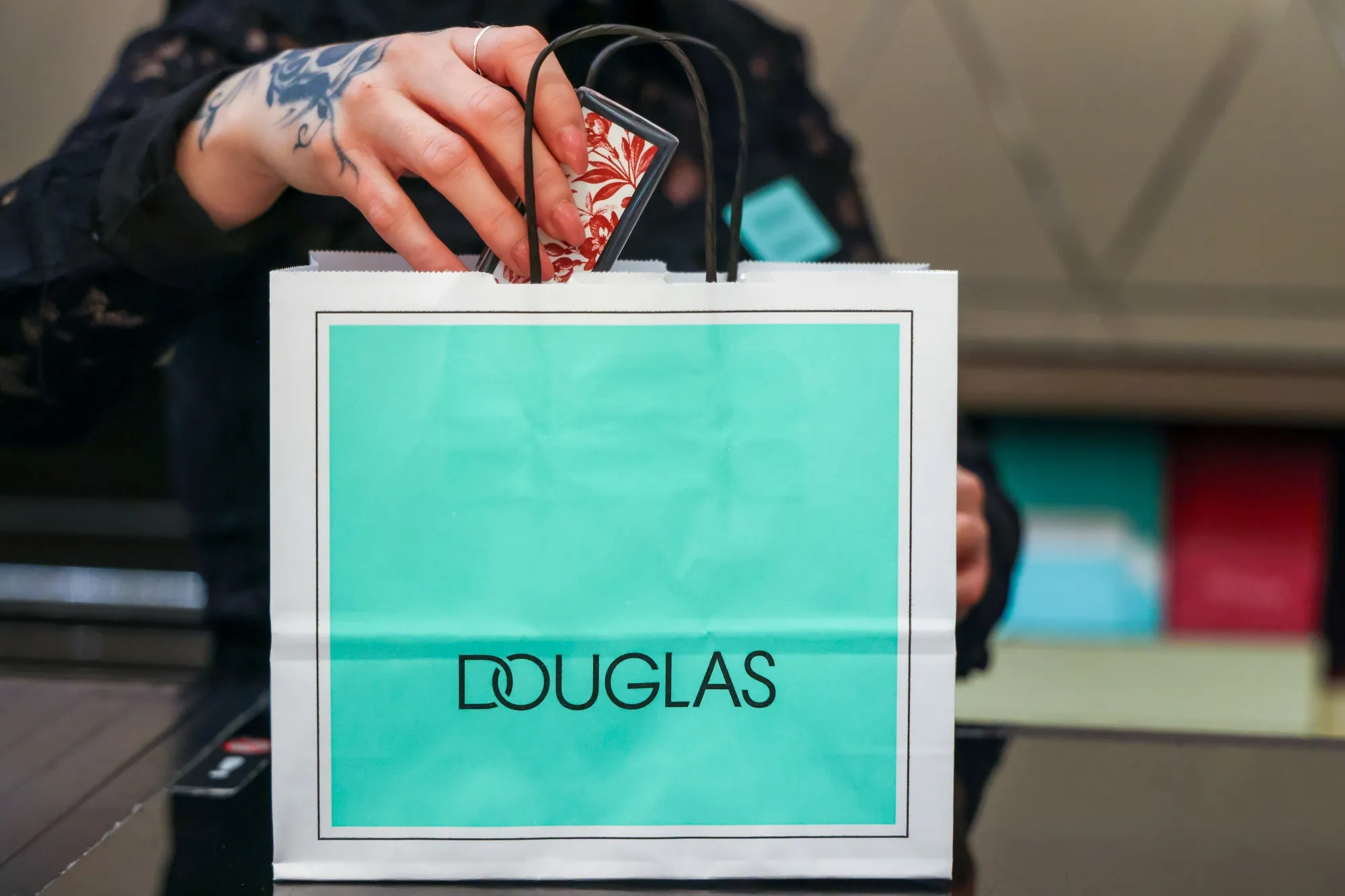 A member of staff places a customer's purchase in a bag at a Douglas store in Frankfurt, Germany