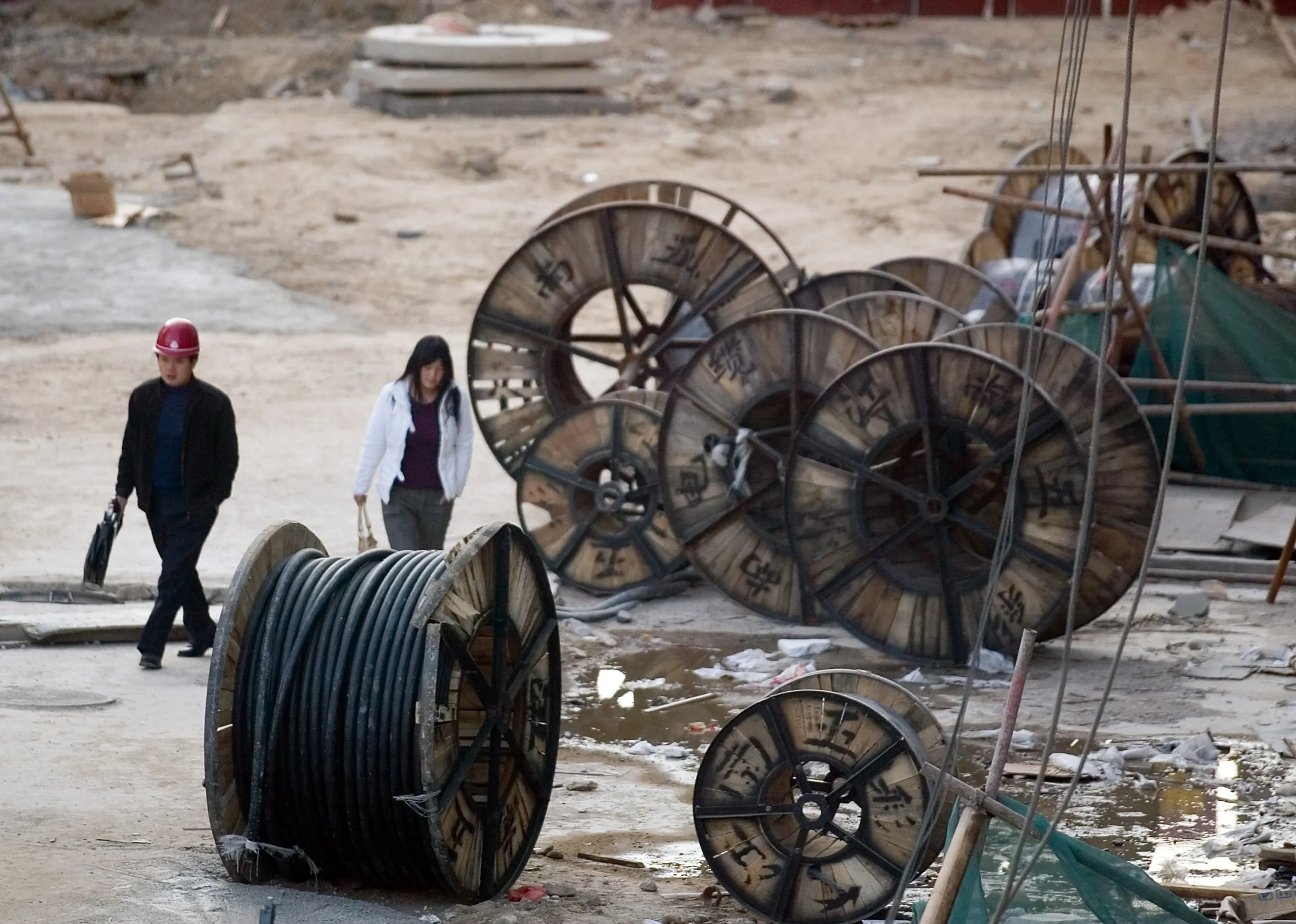 Workers walk past rolls of wiring at a construction site in Beijing, China.