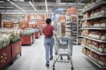 An employee completing an online customer order wheels a shopping cart through a Wal-Mart Stores Inc. outlet in Shenzhen, China.