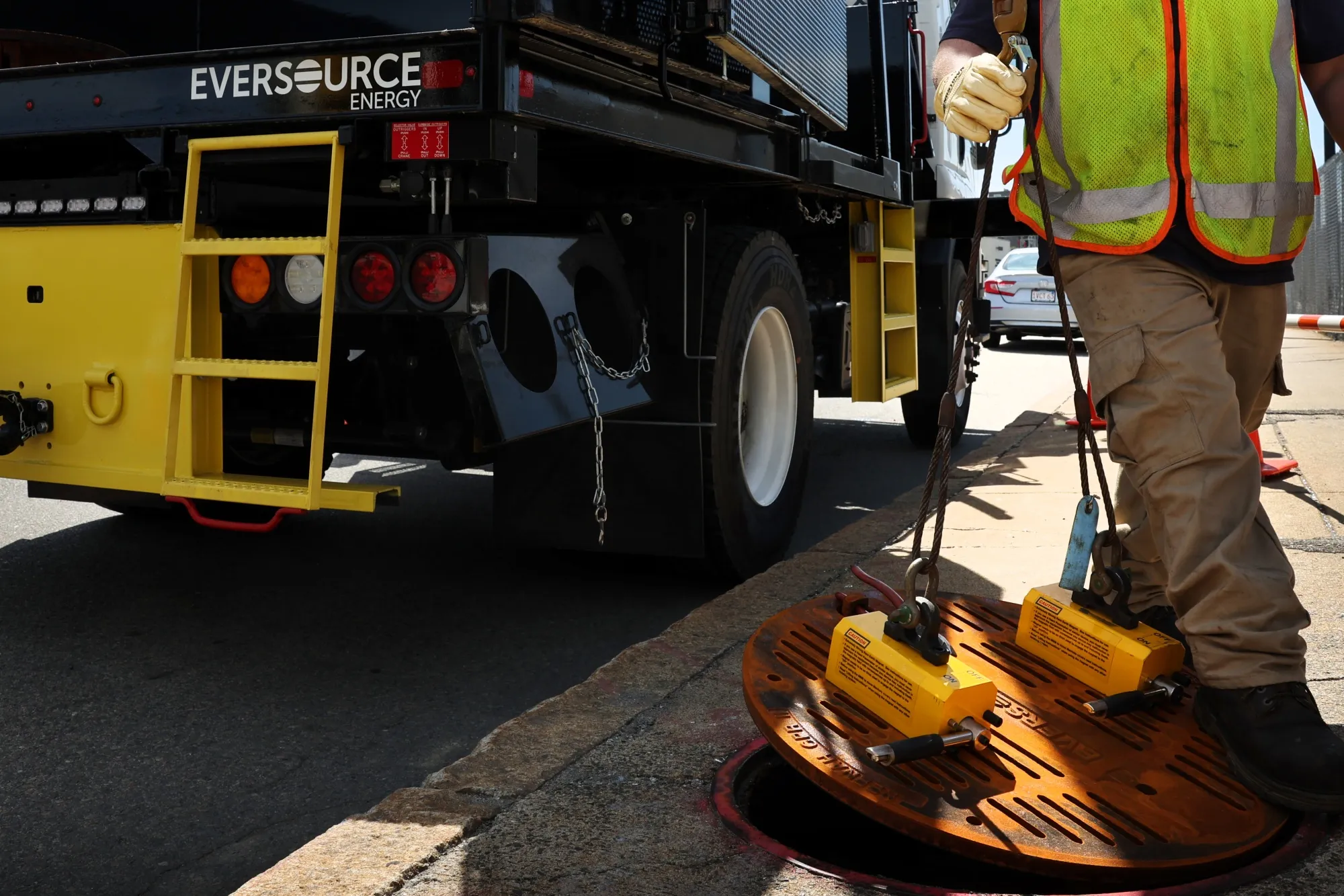 An Eversource lineworker&nbsp;guides a manhole cover into place.
