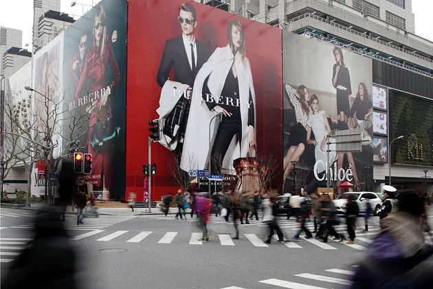 Pedestrians strolling past billboards in Shanghai
