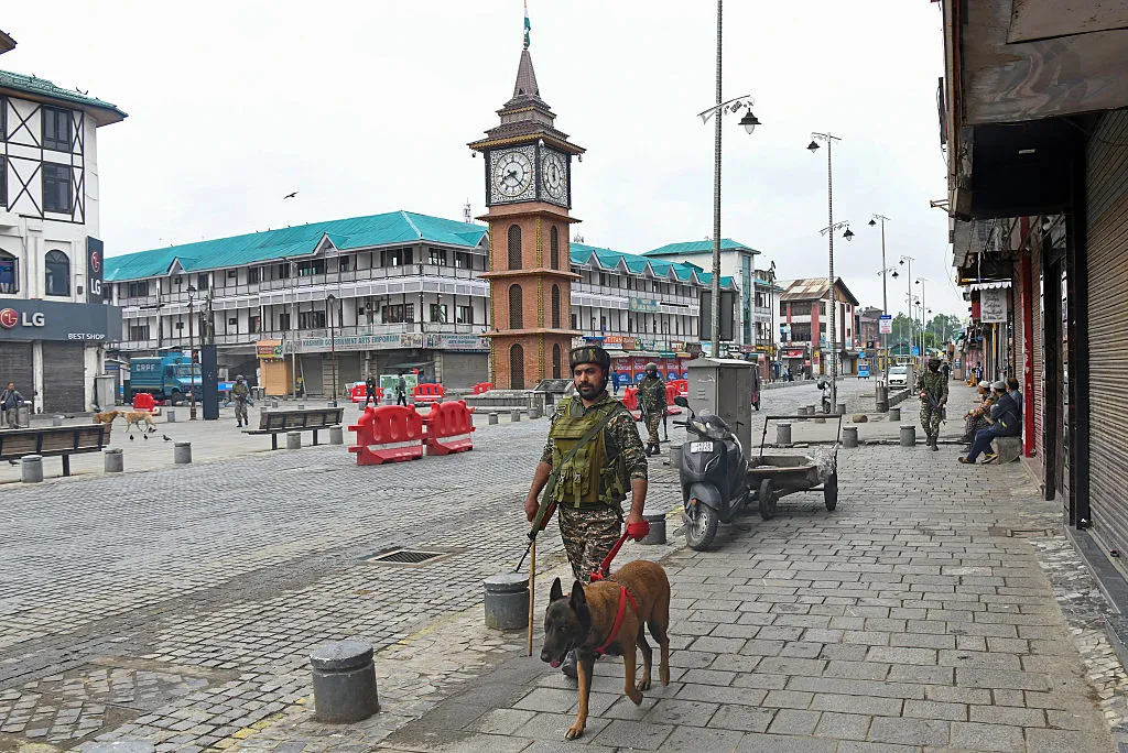 Indian paramilitary soldiers with sniffer dog patrol at a marketplace in Srinagar on May 10.