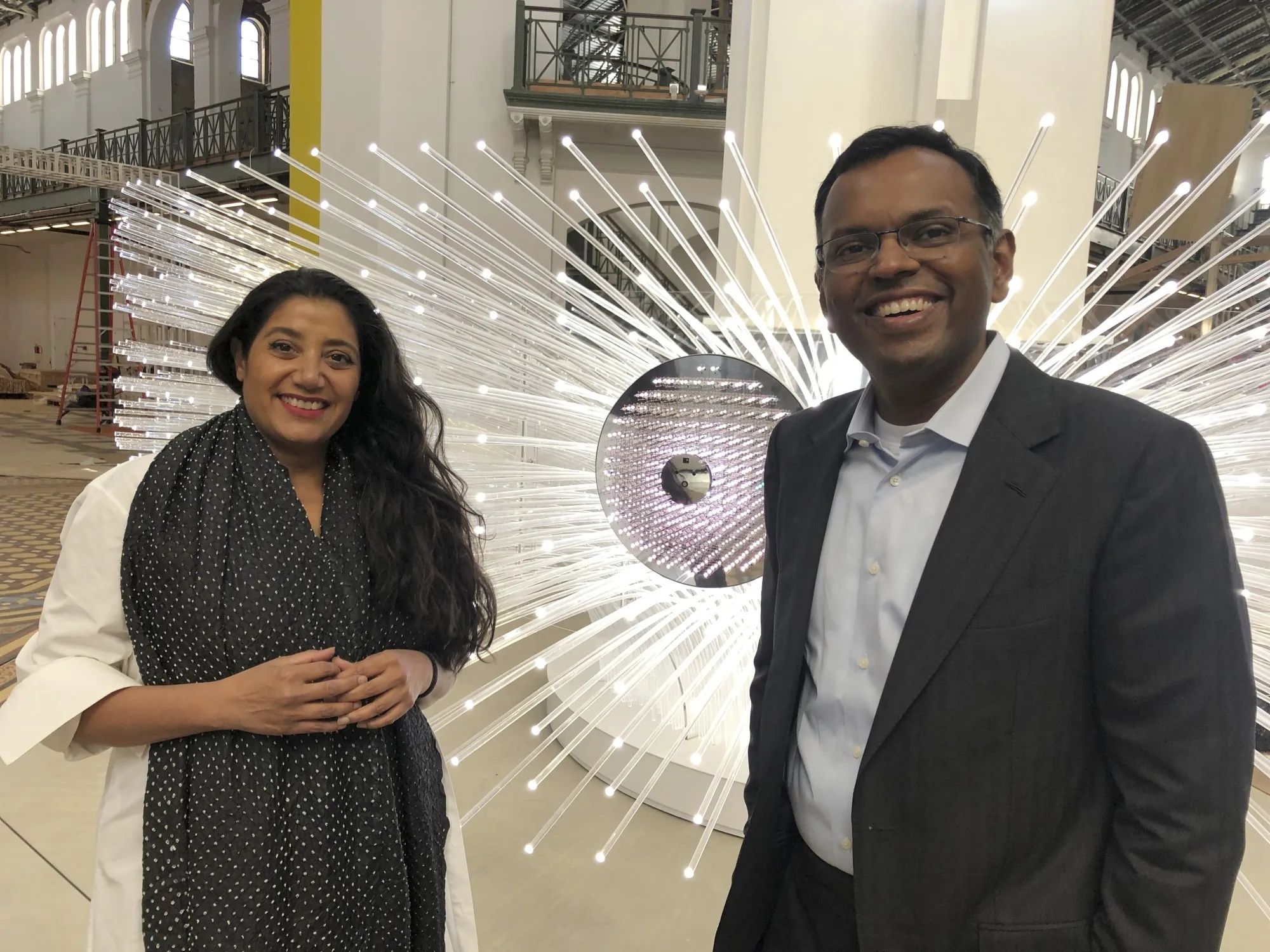 This Oct. 27, 2021, photo shows, from left, artist Suchi Reddy and Swami Sivasubramanian, VP of Amazon Machine Learning at Amazon Web Services, in front of the interactive artwork "me + you" in Washington, D.C. The sculpture uses machine learning to interpret viewers' expressions about the future and incorporate them into the artwork. It is a featured piece of art in the exhibit Futures, which will welcome visitors to the Smithsonian's Arts and Industries Building for the first time in 20 years when the exhibition opens. (AP Photo/Matthew Barakat)