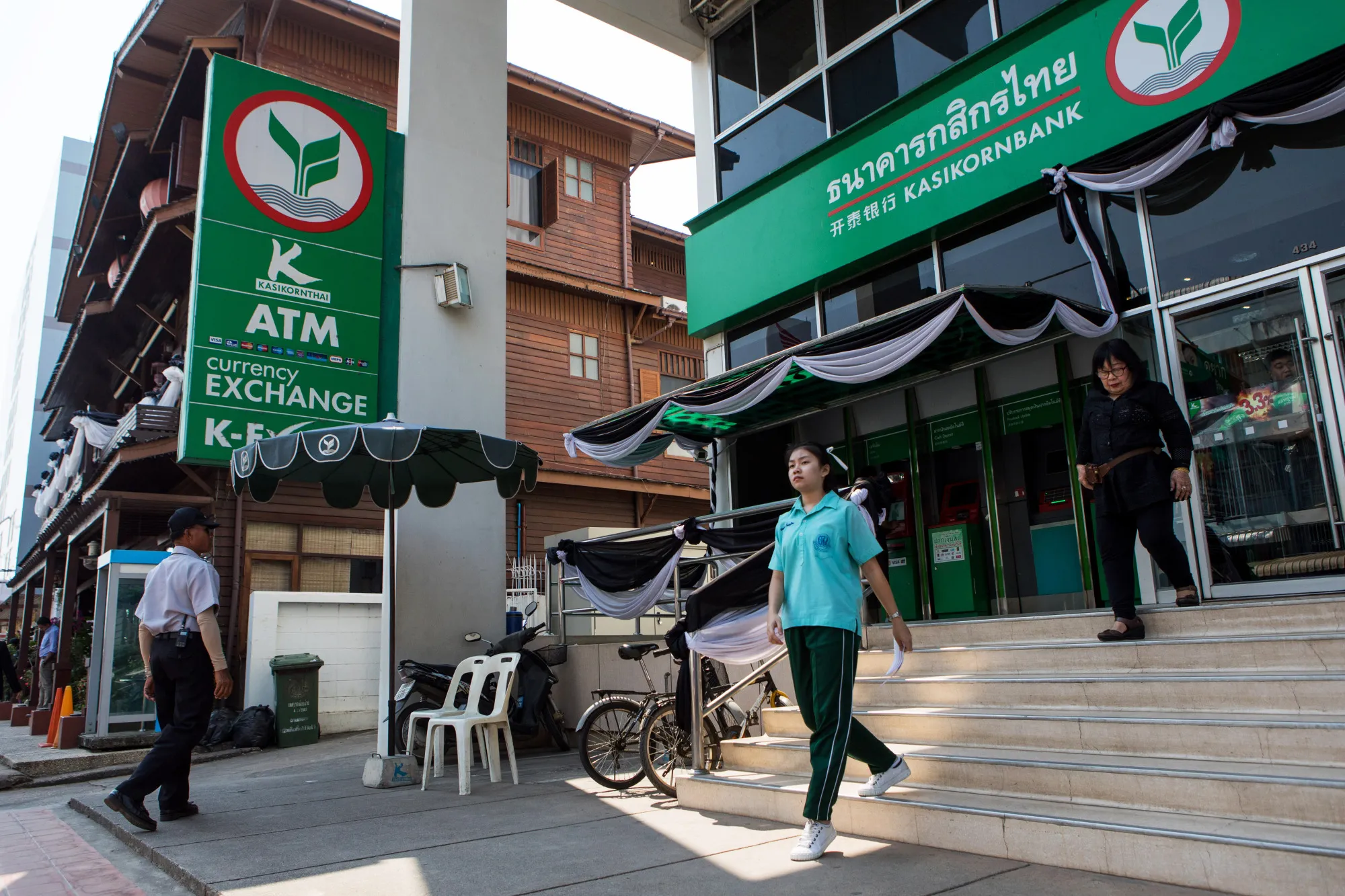 Customers exit a Kasikornbank Pcl branch in Nan, Nan Province, Thailand.