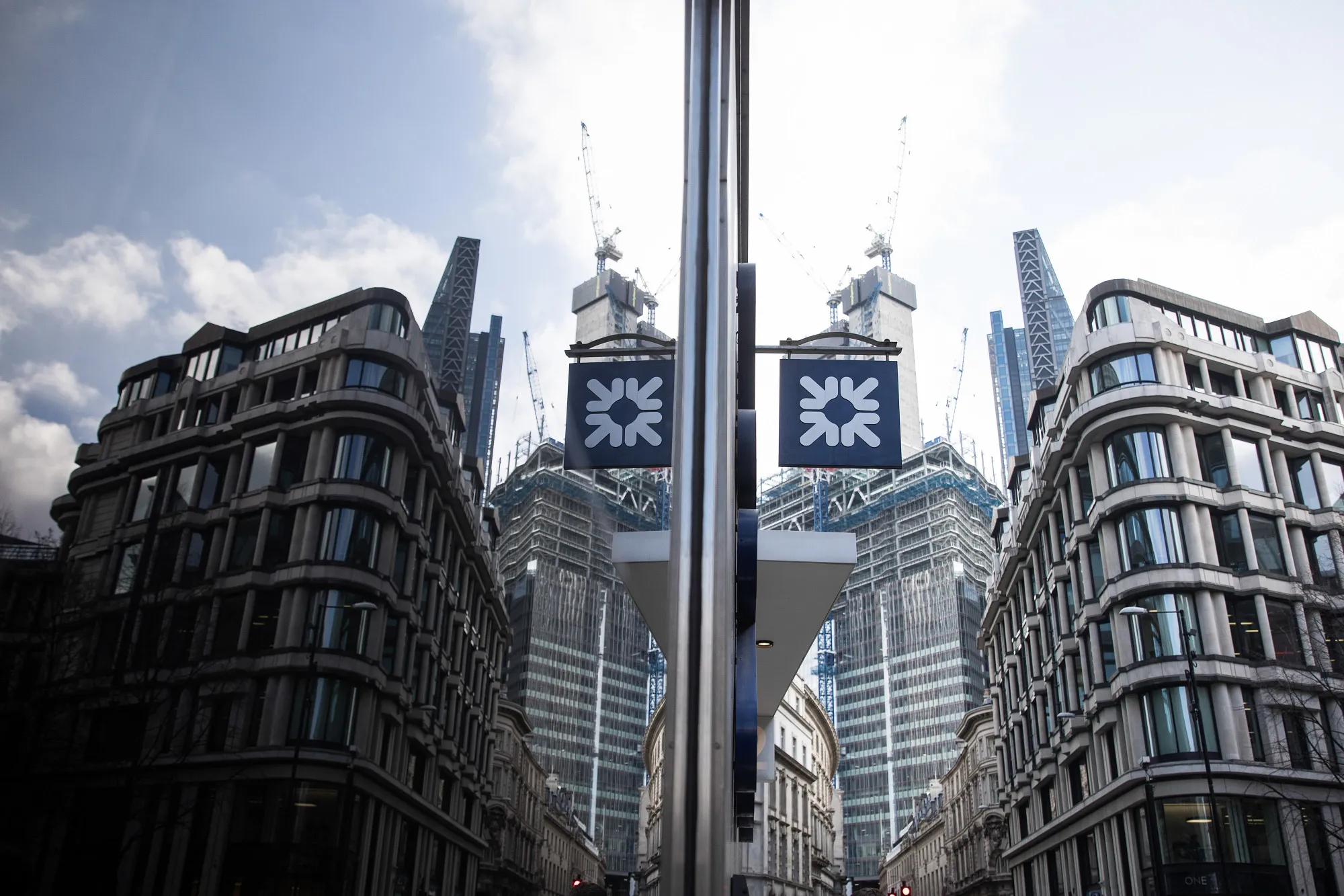 A window reflects a Royal Bank of Scotland Group Plc logo at a bank branch in London.