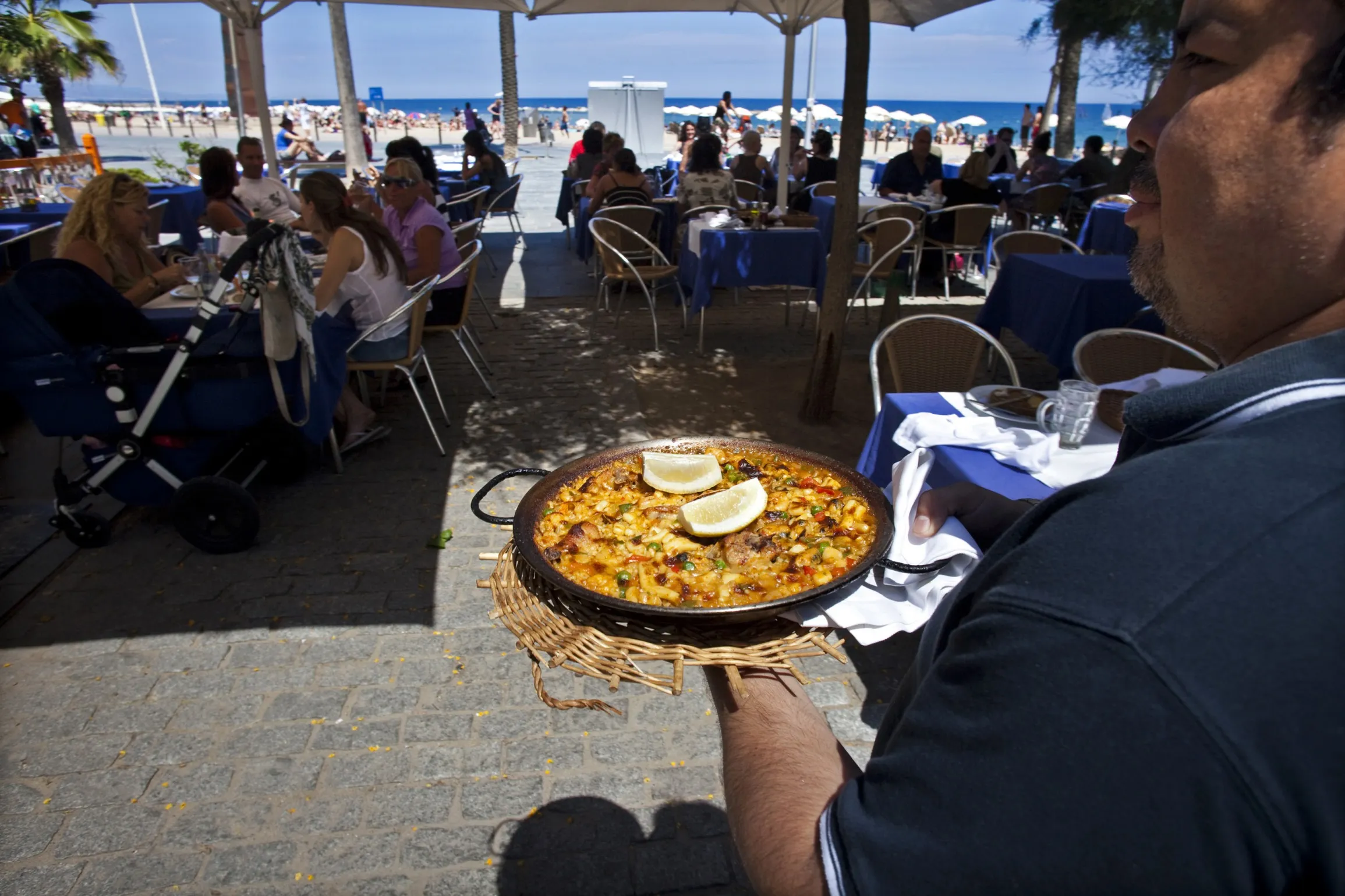 A waiter carries paella in a restaurant on the beach in Barcelona.