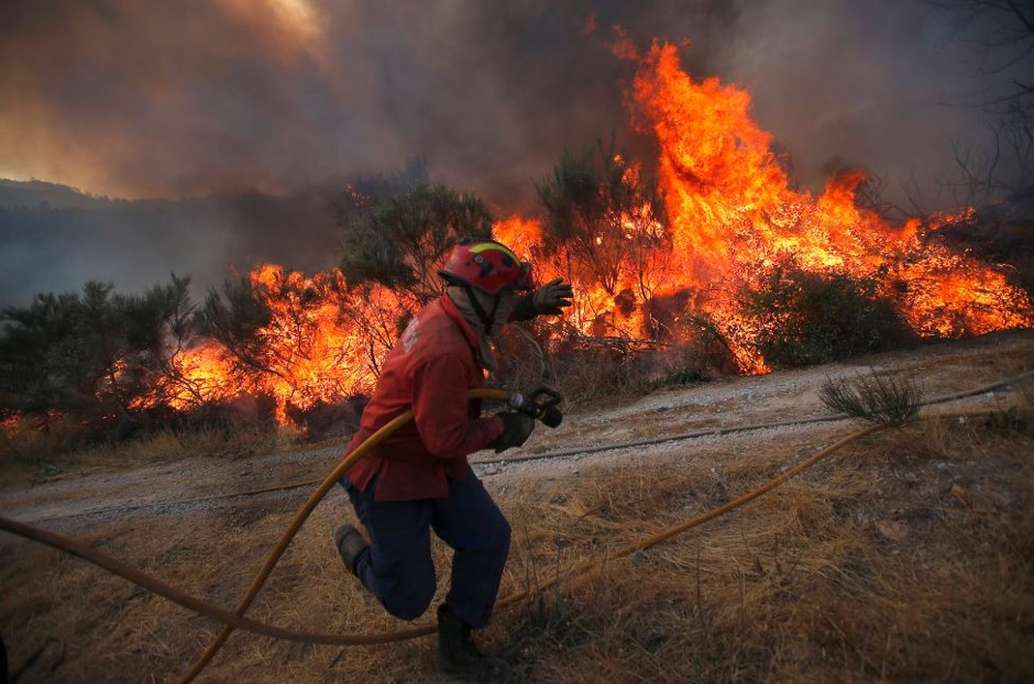 A firefighter battles a deadly forest fire in Portugal in August, 2013.