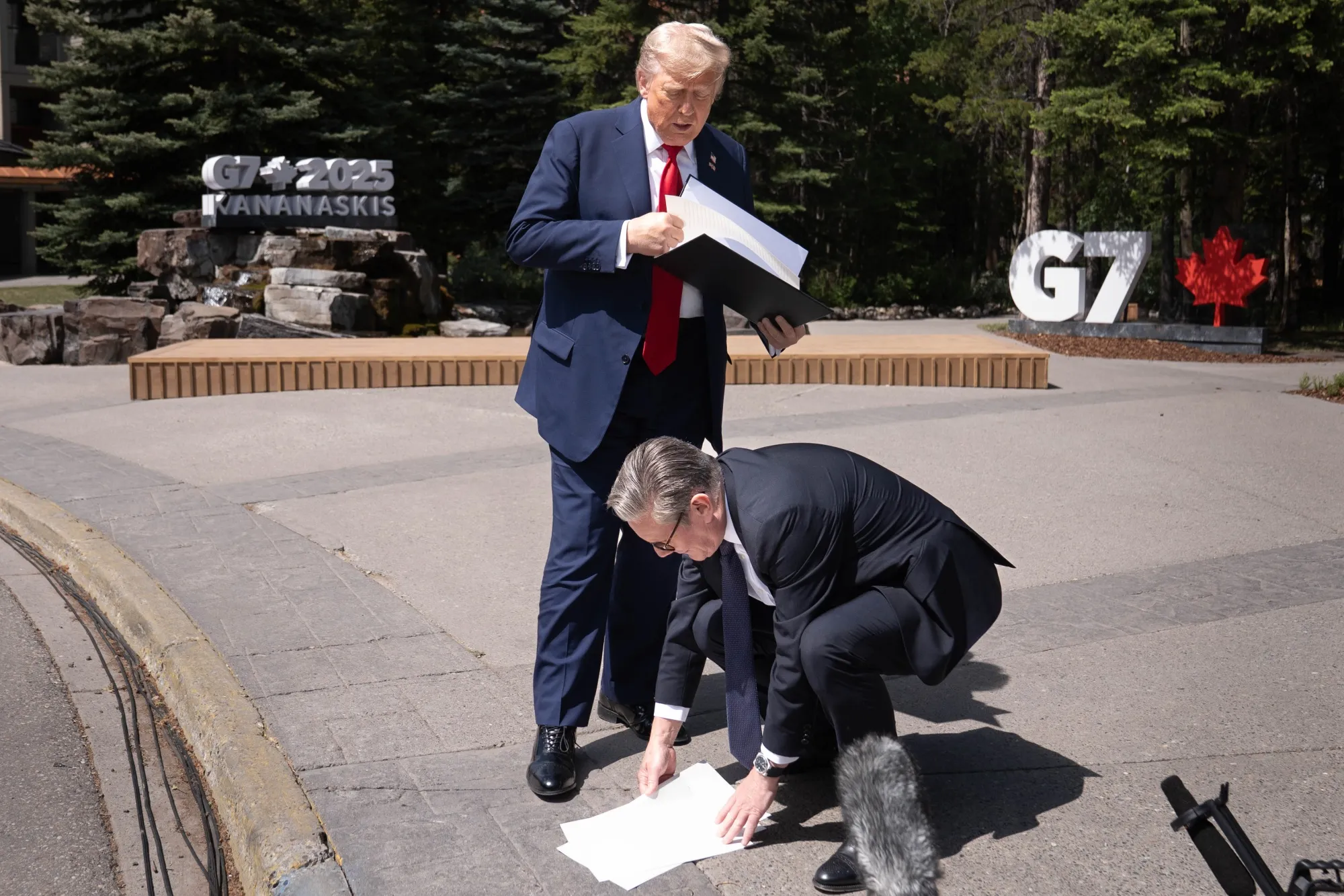 Keir Starmer picks up papers dropped by Donald Trump in Kananaskis, Canada, on June 16.