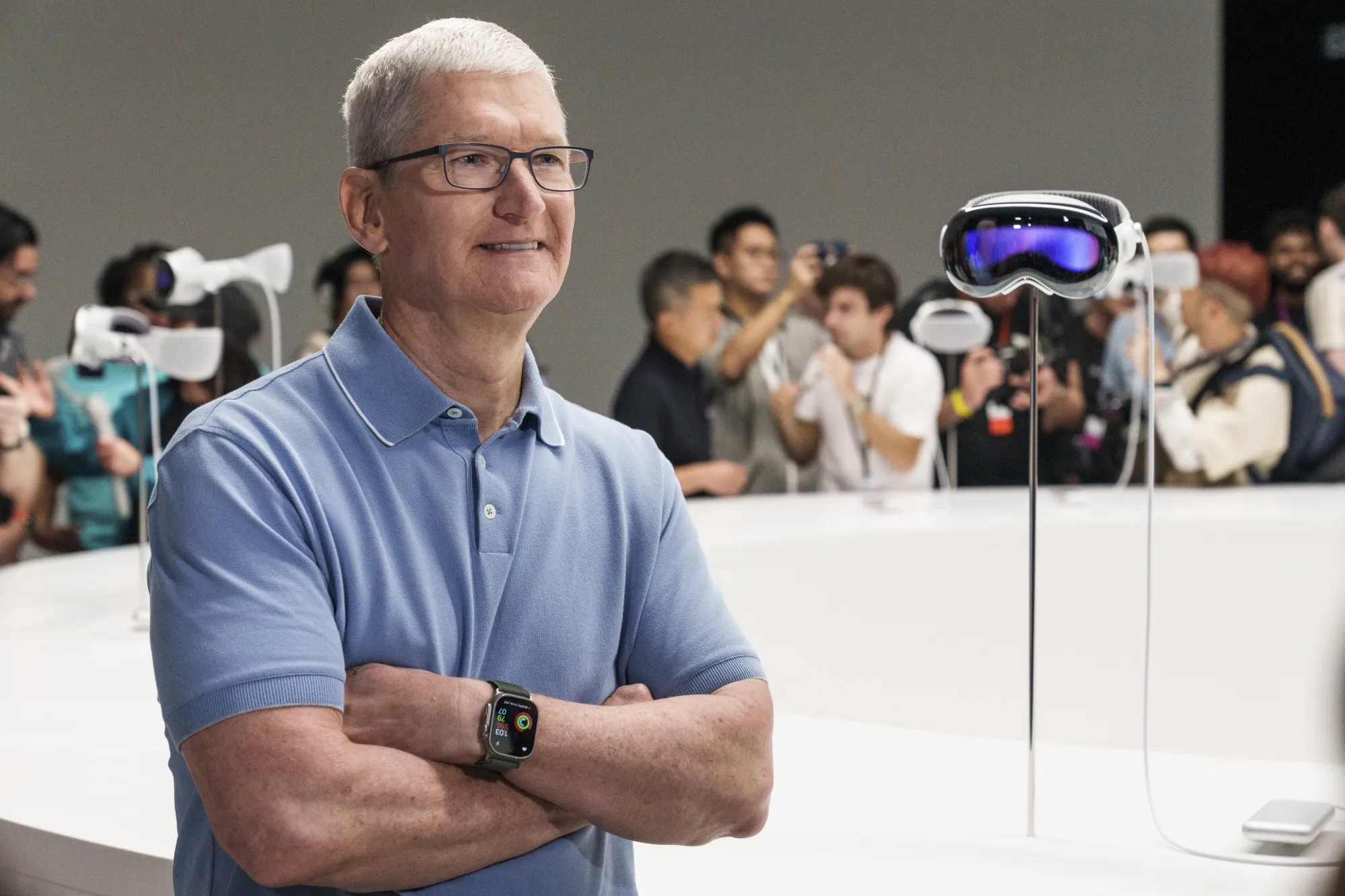 Apple CEO Tim Cook with a Vision Pro headset on display.