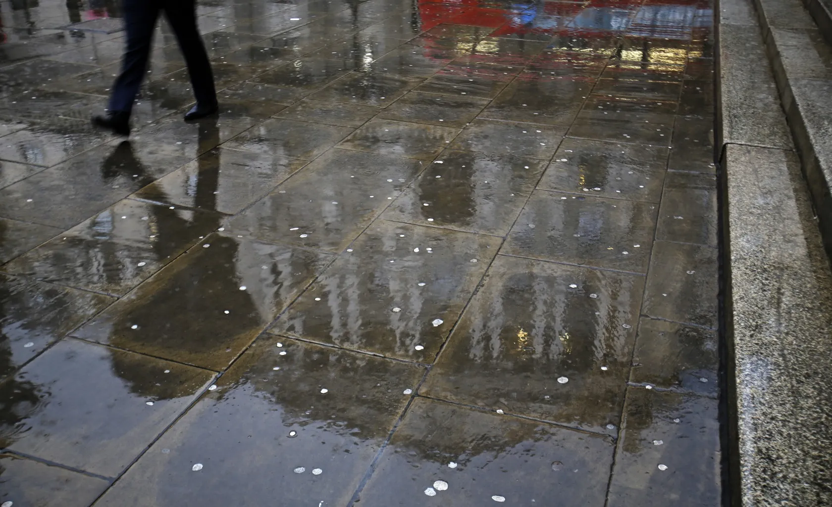 A pedestrian walks past a reflection of the Bank of England in London.