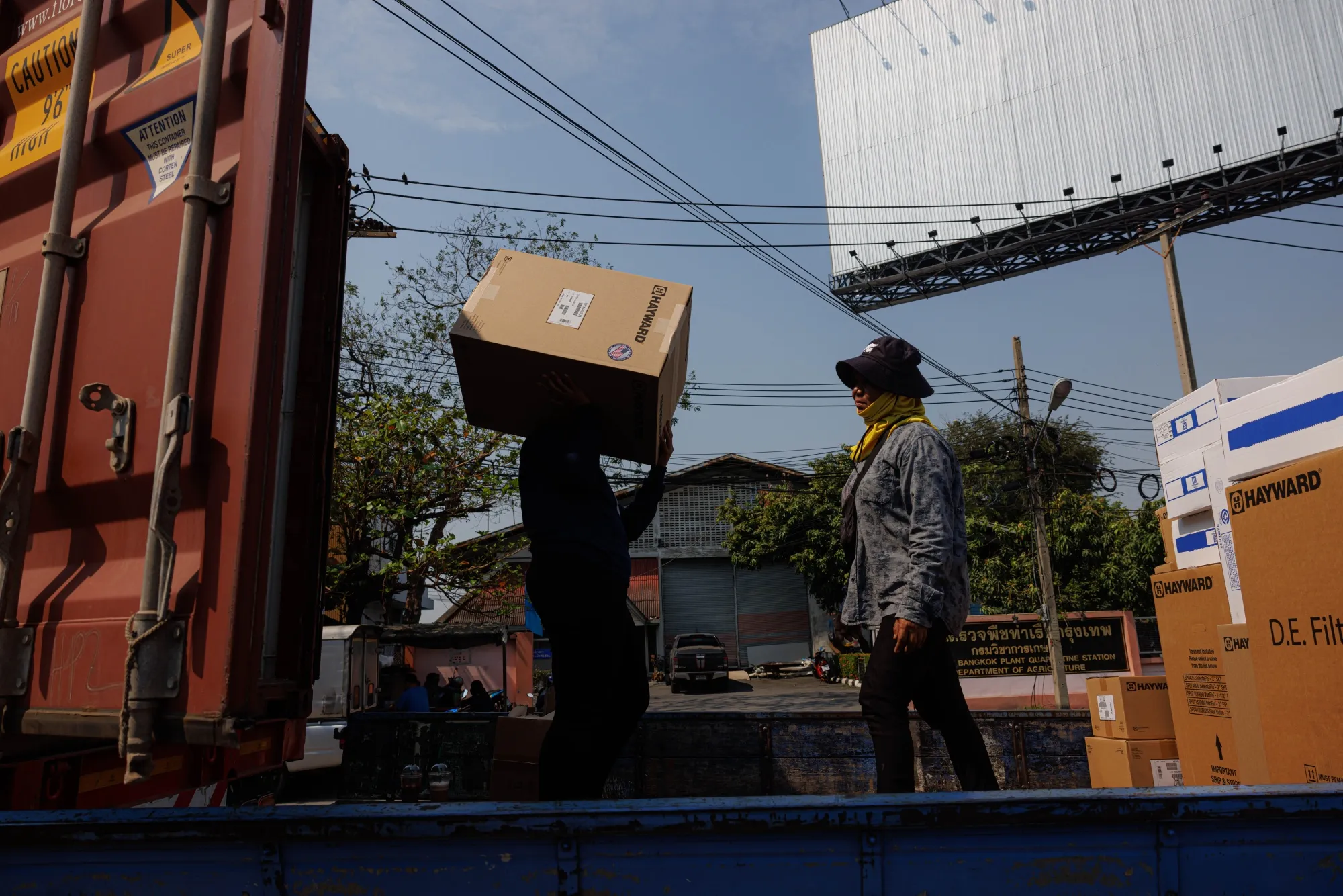 Workers move goods from a cargo container onto a truck near the port in Bangkok.