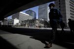 A pedestrian wearing a protective mask walks past the Bank of Japan (BOJ) headquarters, center, in Tokyo, Japan.