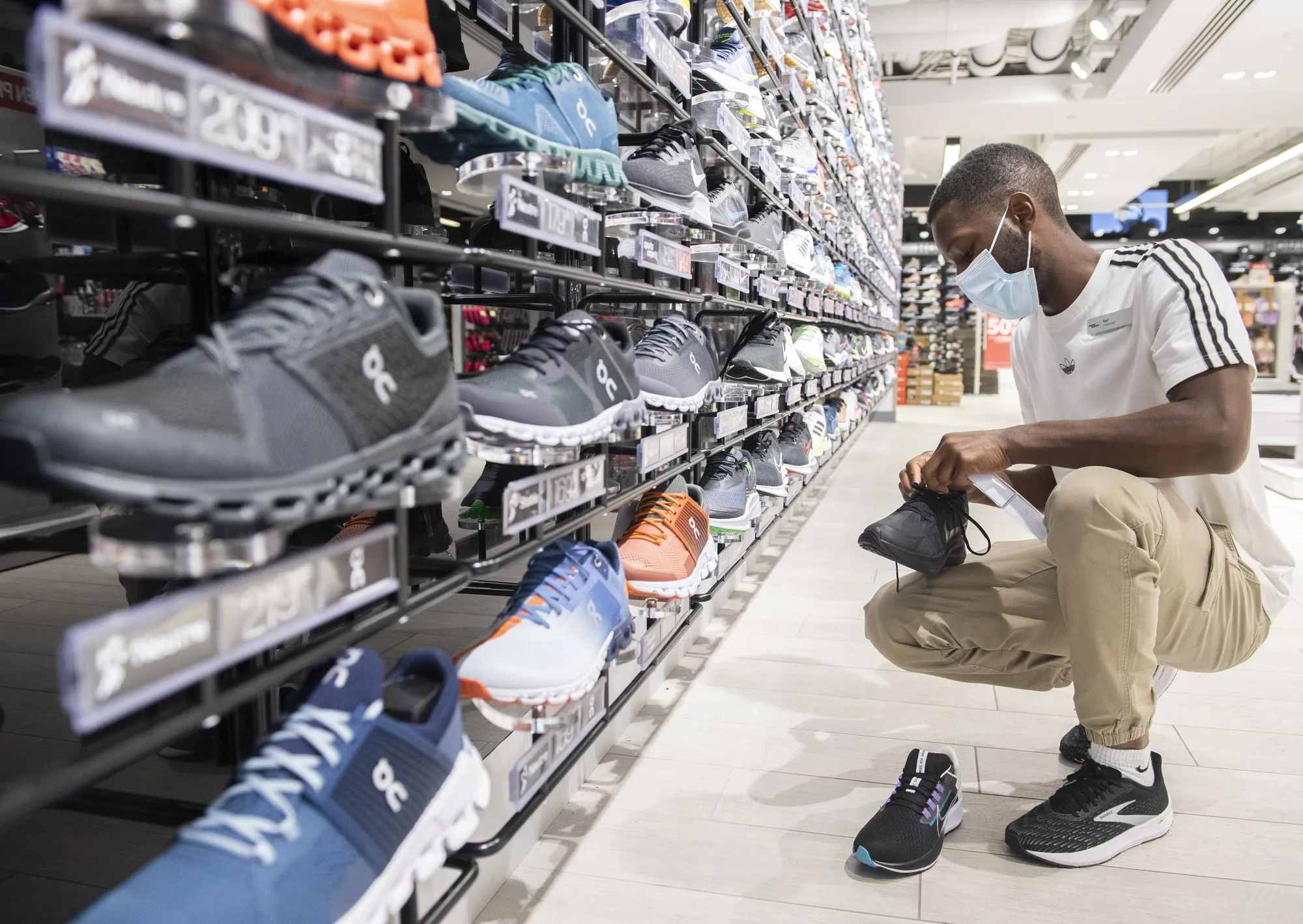 A worker inspects running shoes at a Sports Expertss store on Sainte-Catherine street in Montreal, Quebec, Canada, on Wednesday, Oct. 6, 2021. The Quebec economy is bouncing back faster than was anticipated six months ago, raising the prospect of a smaller budget deficit even as the government faces new expenses to weather the pandemic, the province's finance minister said.