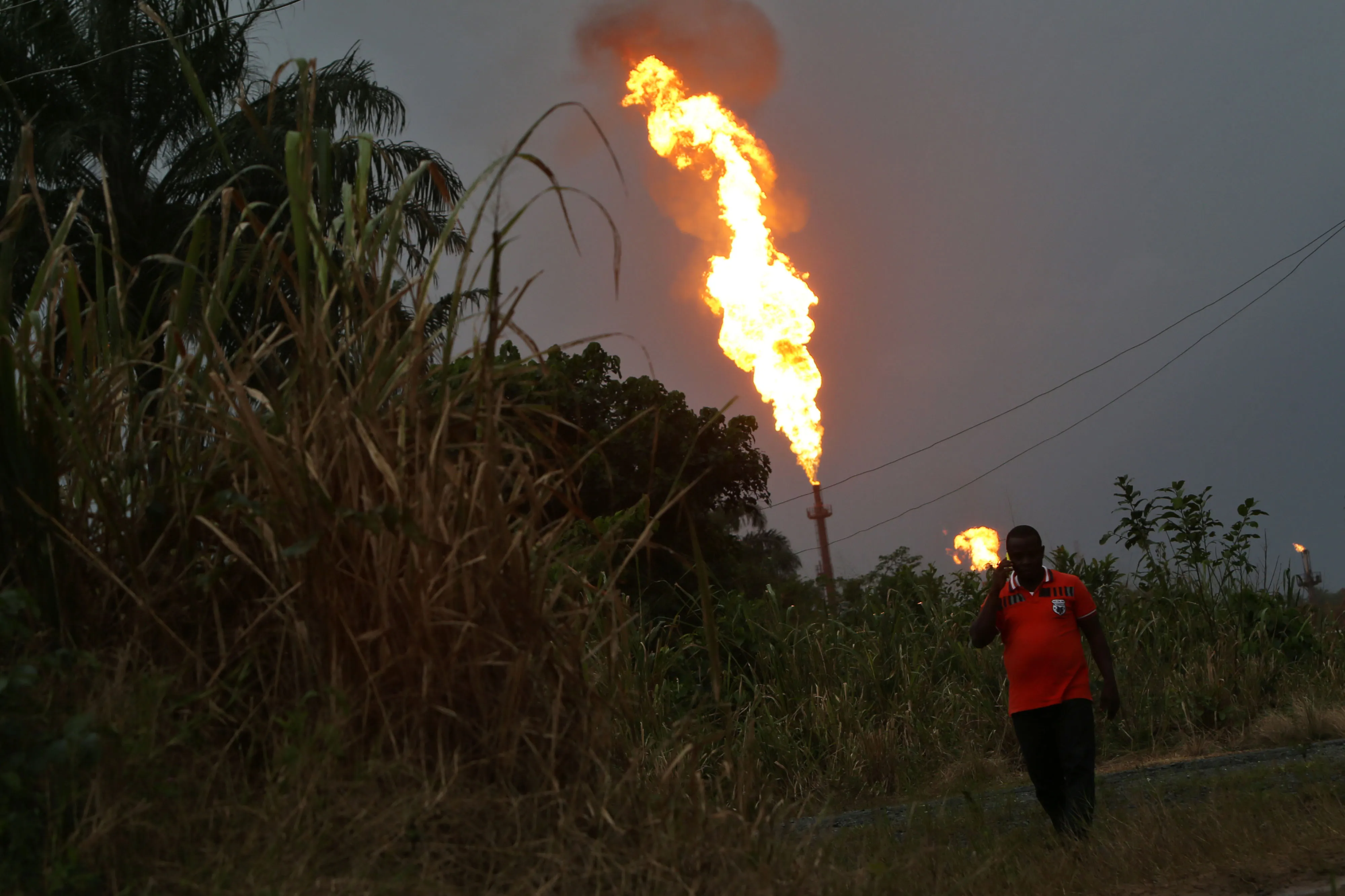 A man walks thr gas flares in Idu, Rivers State, Nigeria.