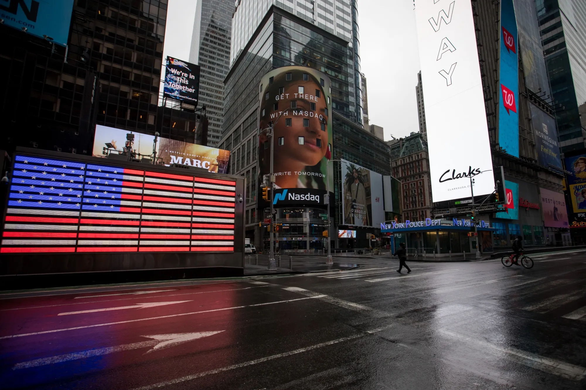 A pedestrian and a cyclist cross the street in the Times Square neighborhood of New York.