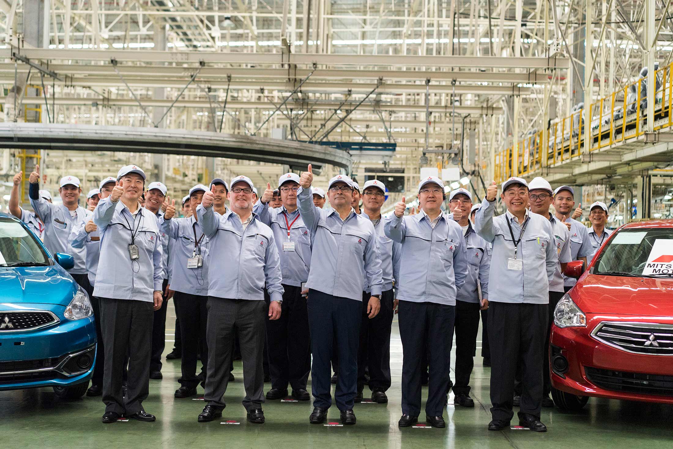 Ghosn (center) poses with managers and workers at a Mitsubishi plant in Thailand.
