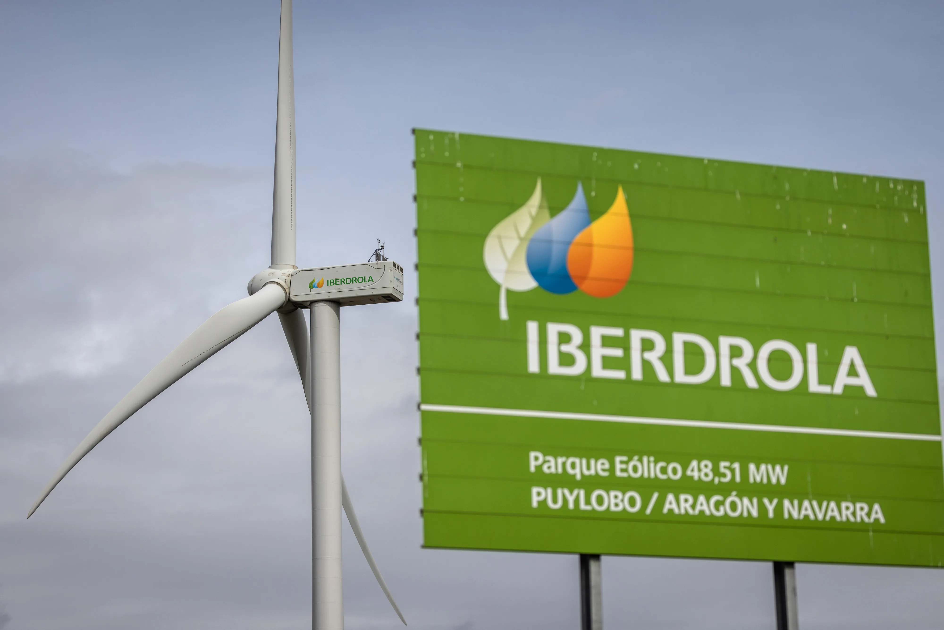 A wind turbine and a Puylobo wind farm sign in Zaragoza, Spain.
