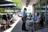 A server wearing a protective mask assists customers in the outside seating area of a restaurant.