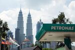 A Petroliam Nasional Bhd. (Petronas) gas station stands in front of the Petronas Twin Towers, second right, in Kuala Lumpur.