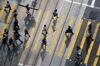 Commuters cross a street in the business district of Central in Hong Kong, China, on Monday, Aug. 18, 2014. Slowing economic growth and rising unemployment in Hong Kong may stoke more unrest in the city, which is grappling with a debate over how to pick its next leader in 2017.