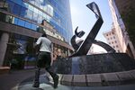 An employee passes the 'Battle of the Markets' sculpture outside the stock exchange in Johannesburg.