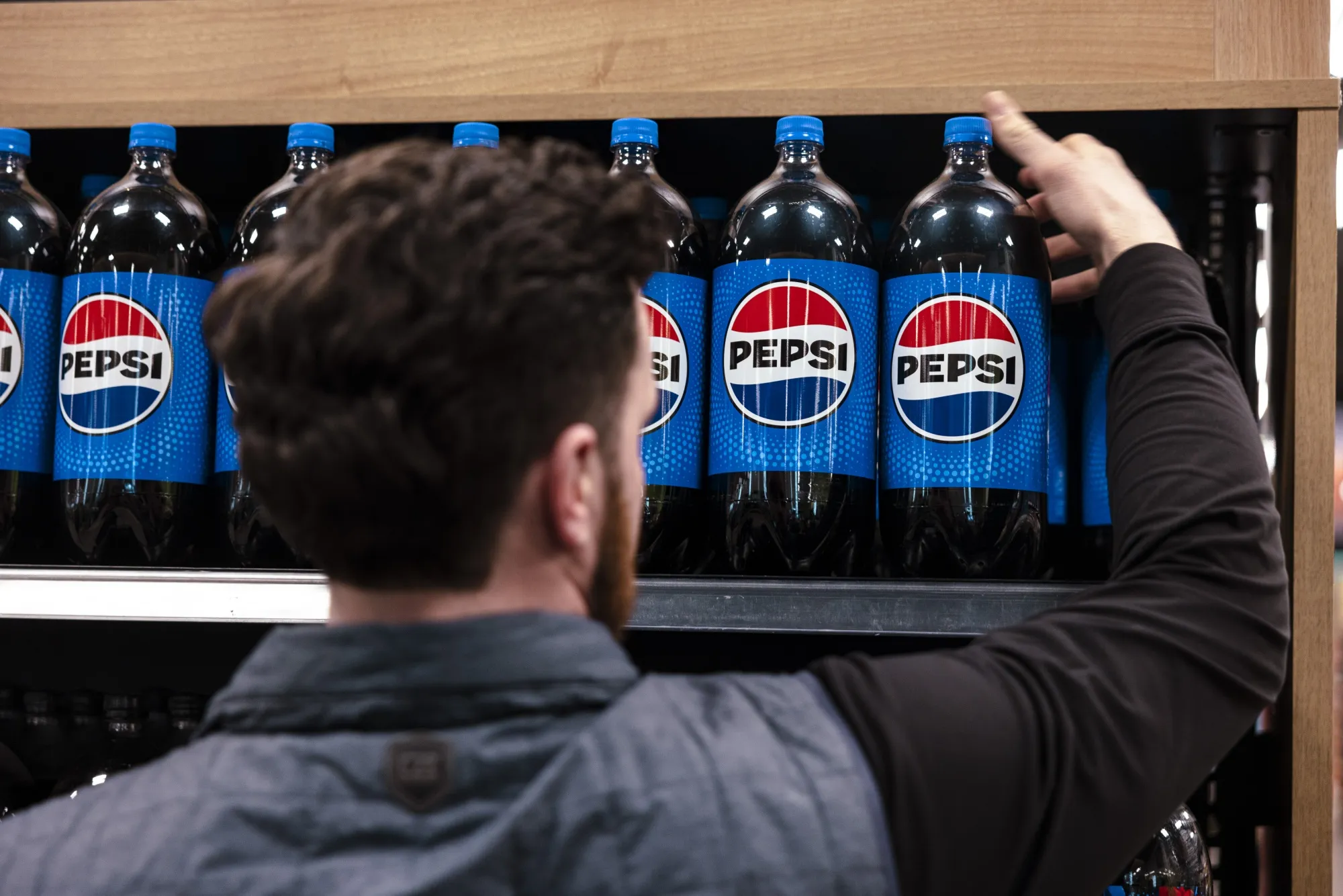 A worker arranges bottles of Pepsi on a shelf at a supermarket in Clifton Park, New York.