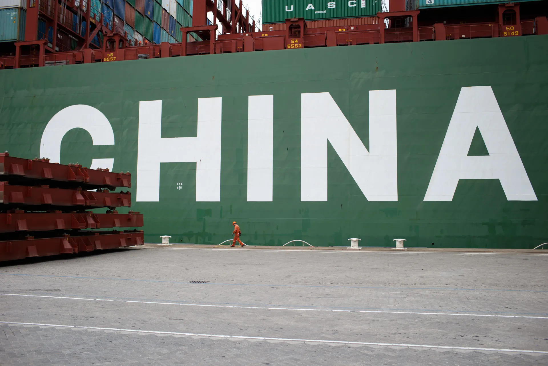 A dock worker walks on the quayside as a container ship, operated by China Shipping Group Co., sits moored in the Port of Rotterdam.