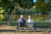 Senior Couple Sitting By The Lake In Autumn
