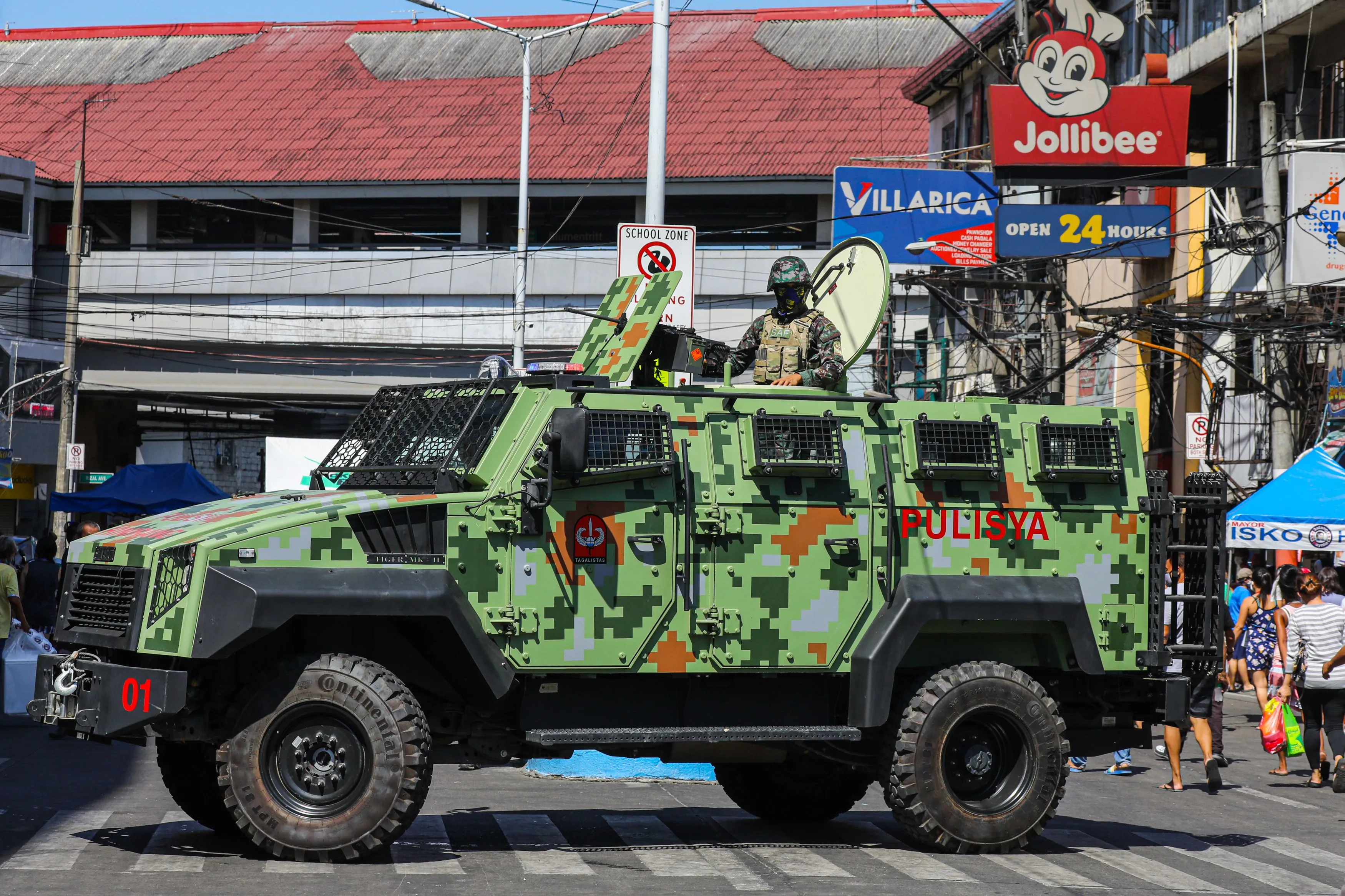 A member of the Philippine National Police Special Action Forces watches from an armoured van while people shop at a market during a government imposed lockdown in Manila.