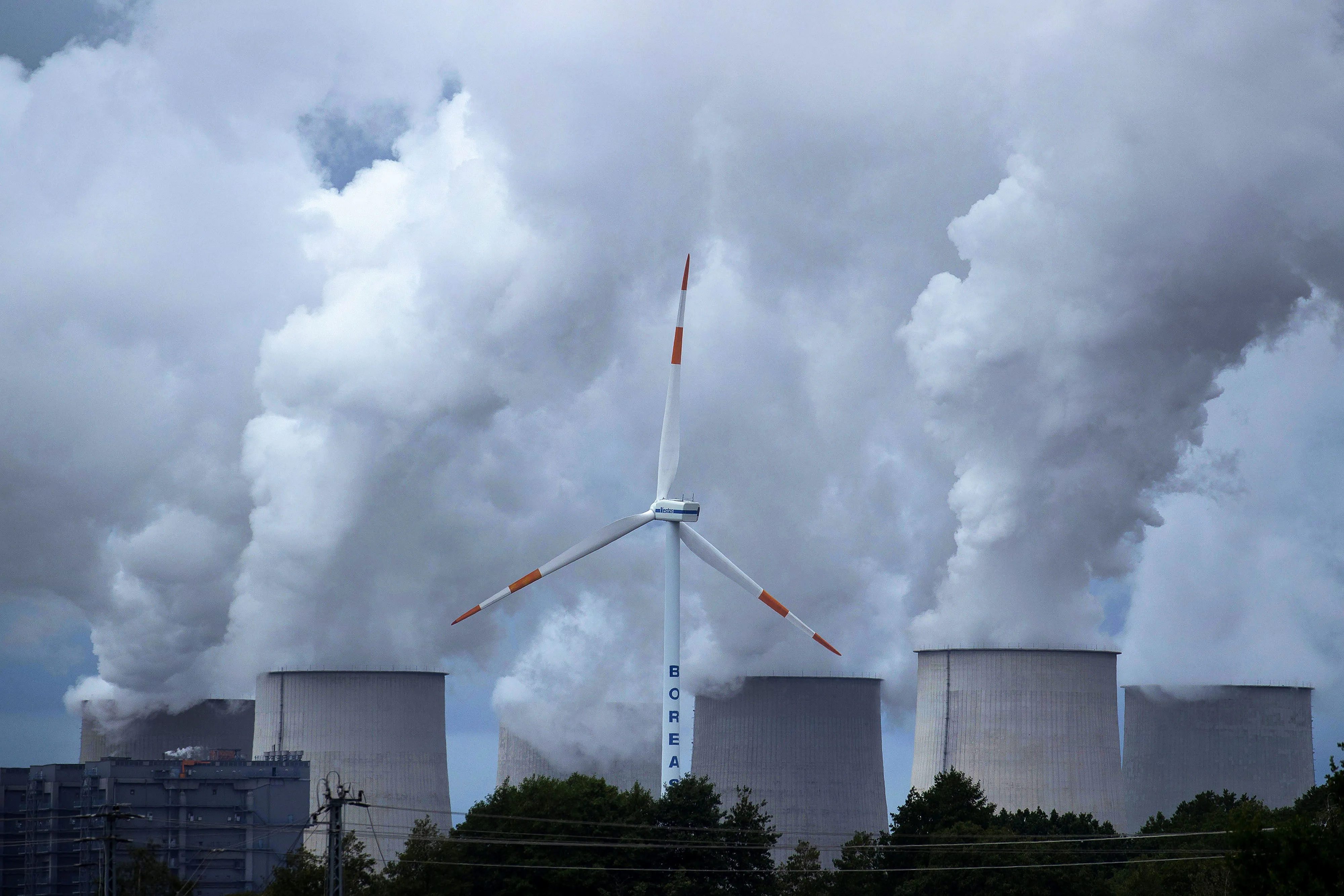 A wind turbine operates near emissions rising from the Jaenschwalde lignite fired power plant, in Barenbrueck, Germany.