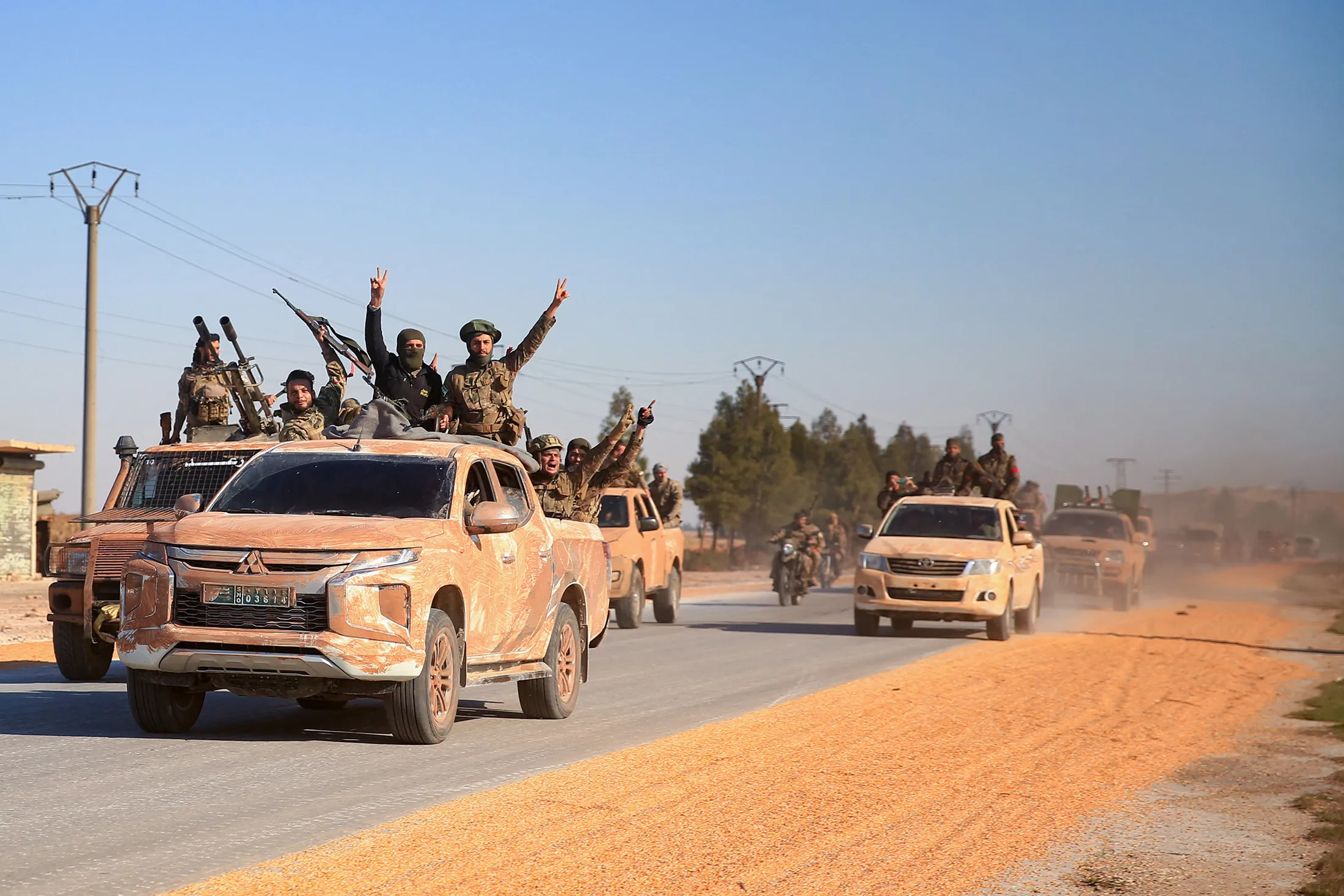 Anti-government fighters ride military vehicles as they drive along a road in the eastern part of Aleppo province on Dec.&nbsp;1.