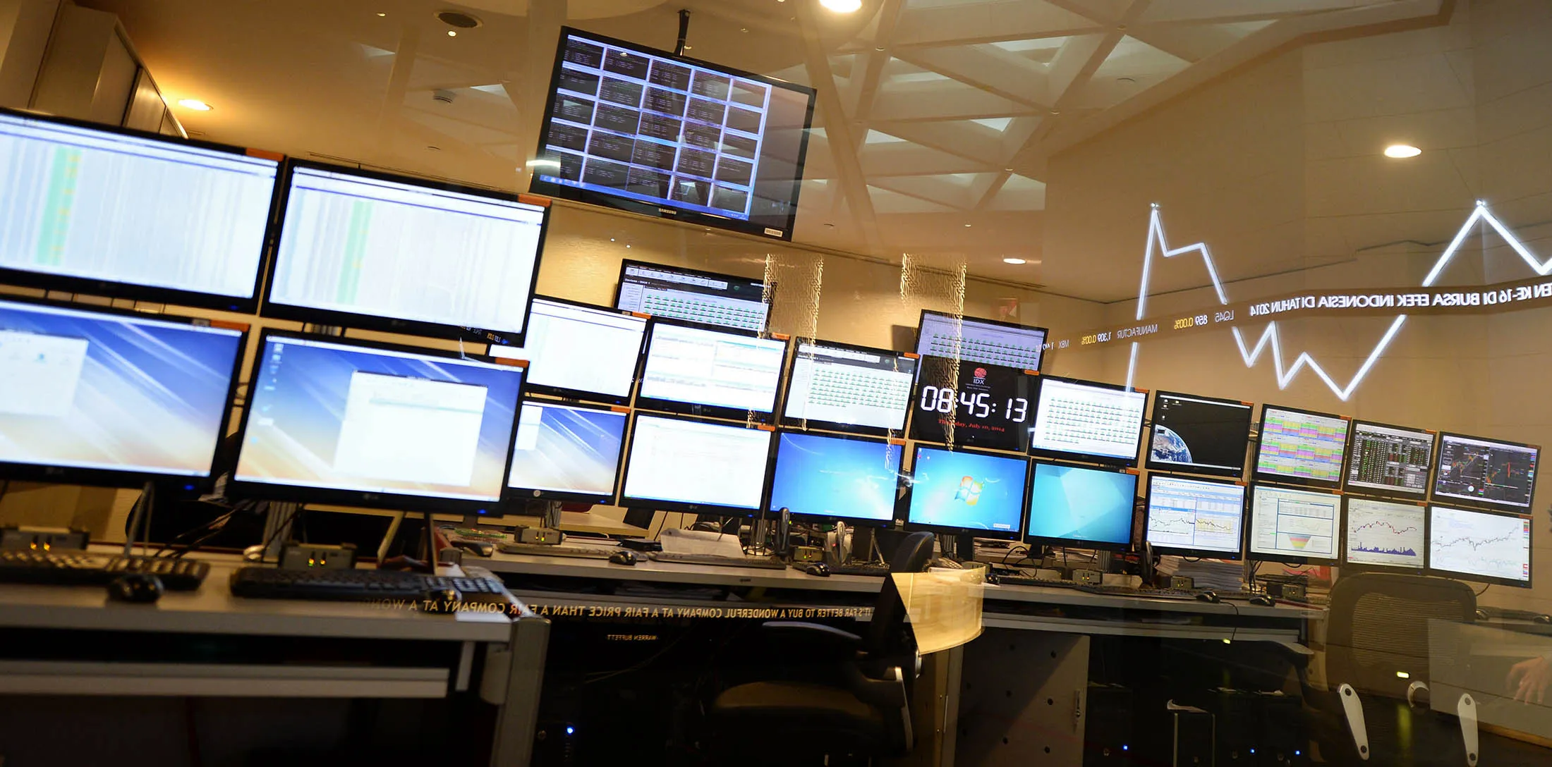An employee monitors market data on computer screens as a stock ticker is reflected on a glass window inside the Indonesia Stock Exchange (IDX) in Jakarta, Indonesia, on Thursday, July 10, 2014. Indonesian stocks rose to a one-year high and the rupiah touched the strongest level in seven weeks after Joko Widodo said unofficial counts at polling booths showed him winning yesterday's presidential race.
