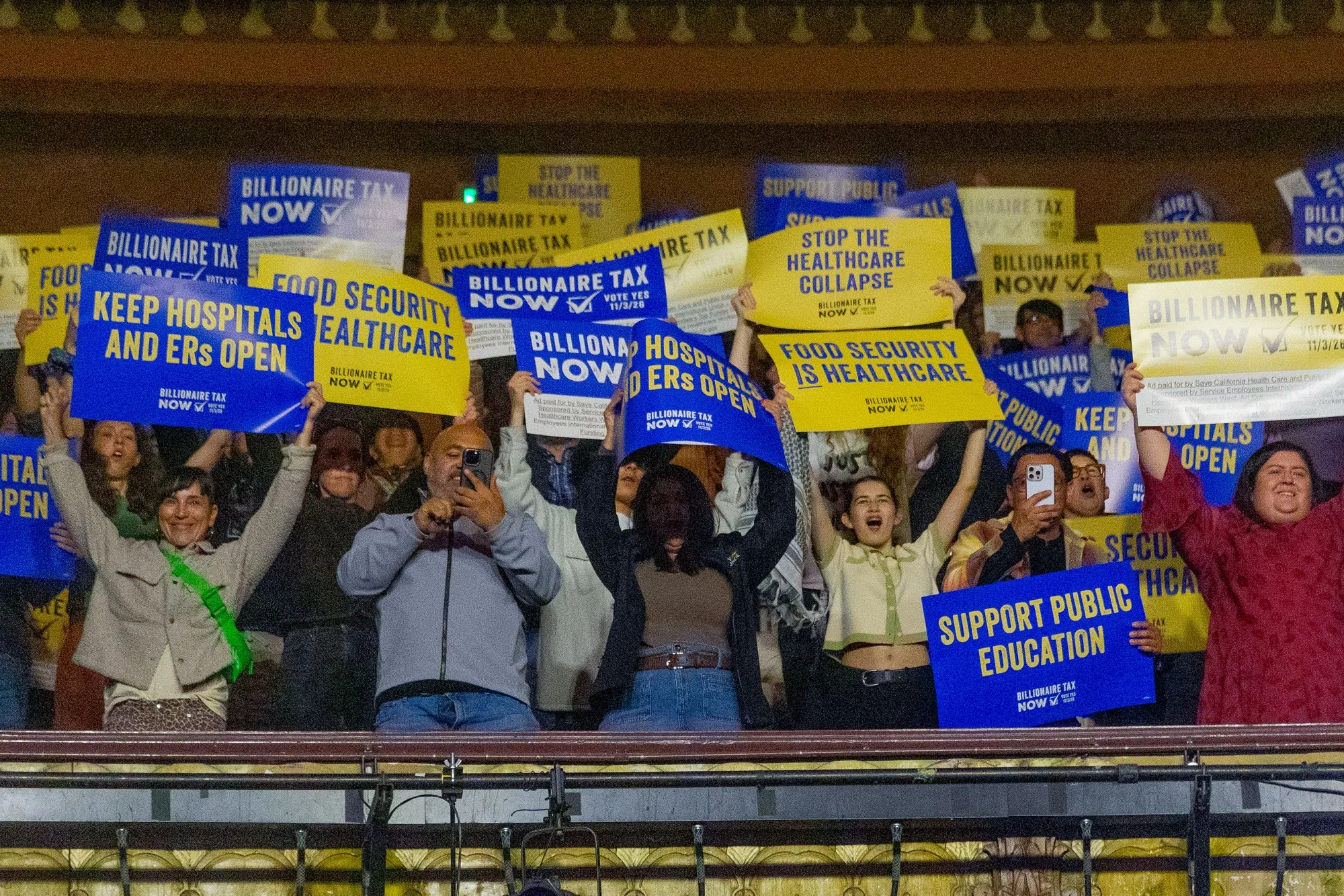 Attendees hold signs during a campaign kickoff event for the California Billionaire Tax Act.