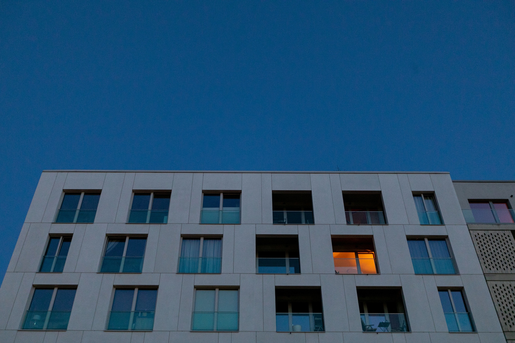 A light on in a home within a block of apartments at dusk in Berlin.