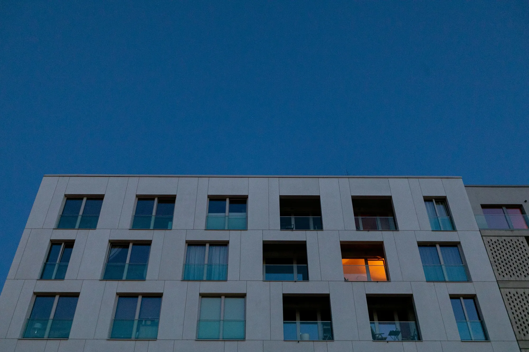 A light on in a home within a block of apartments at dusk in Berlin.
