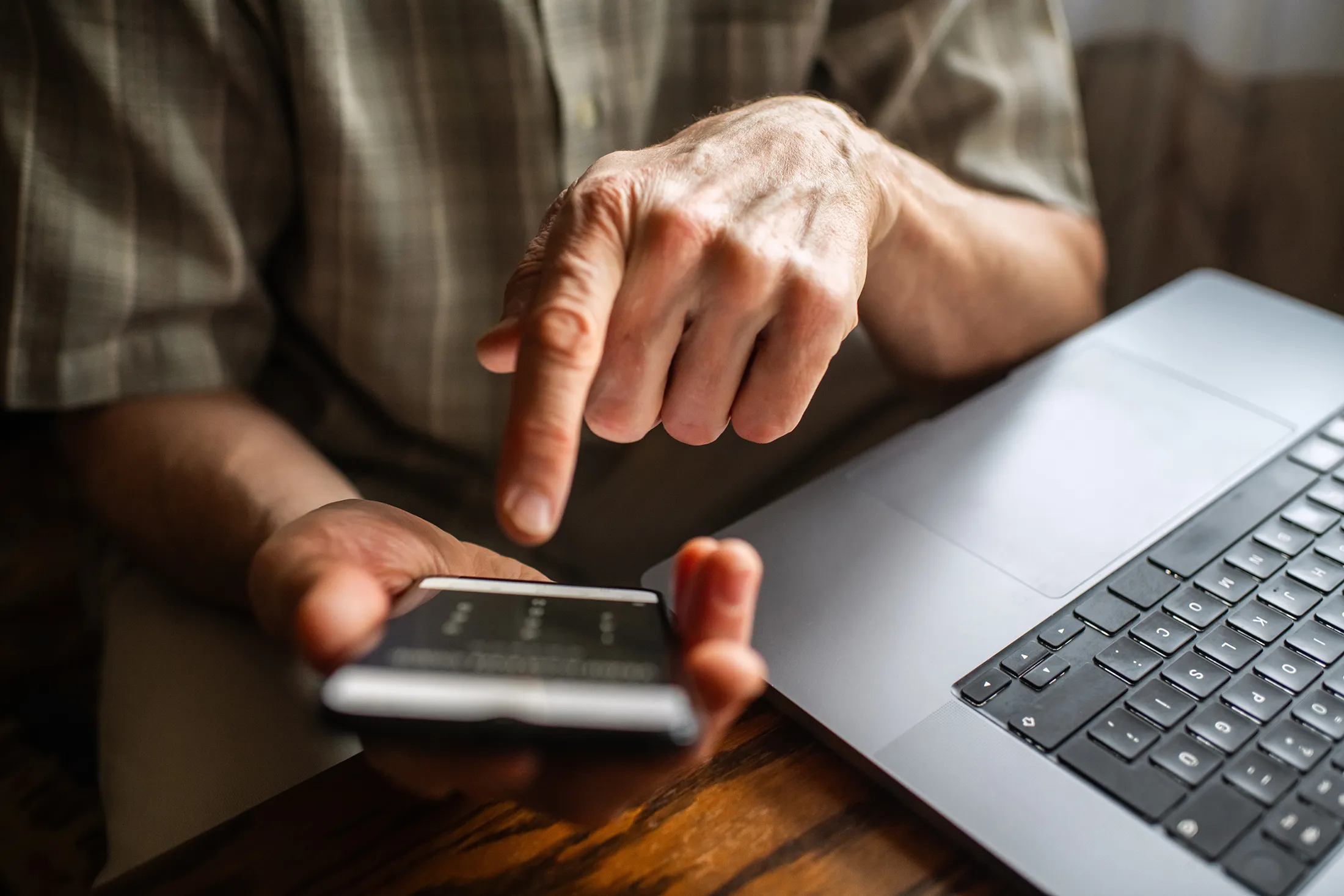 Senior man at home entering verification code in smartphone, fraud prevention concept.