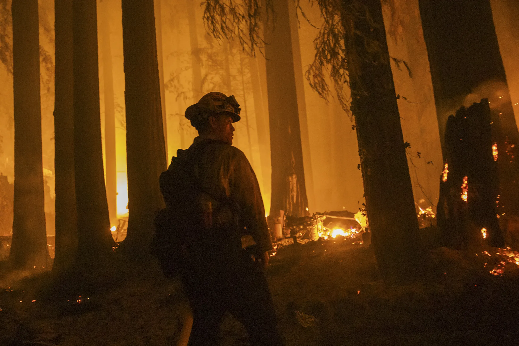 A firefighter with the Jameson Creek CDF station fights a fire on a property on Acorn Drive during the CZU Lightning Complex fire in Santa Cruz County, California, U.S., on Thursday, Aug. 20, 2020. More than 360 blazes are burning in California, forcing mass evacuations in the northern part of the state and creating an air quality emergency.
